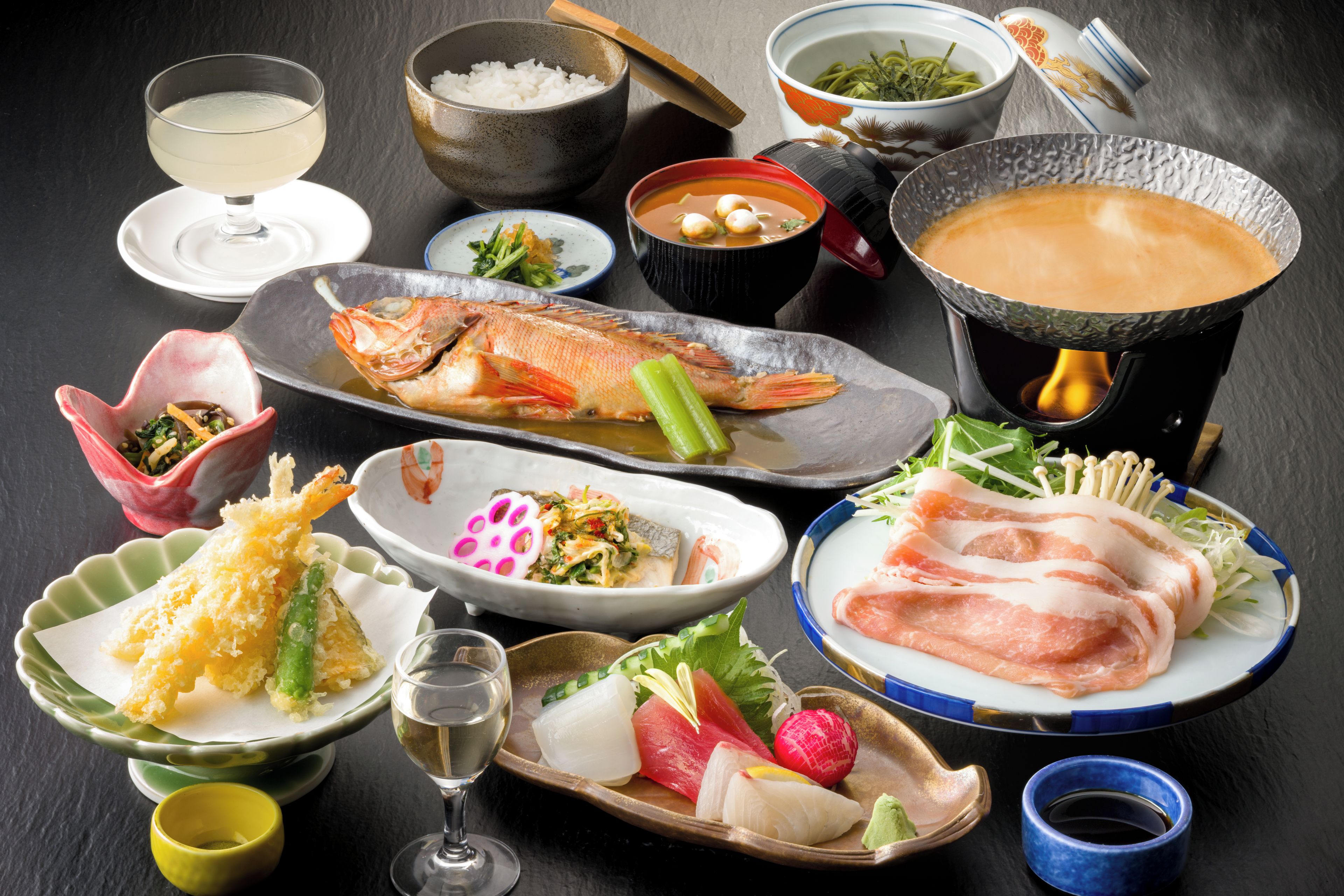 Diversidad de platos japoneses, como sushi, tempura y un caldo caliente.