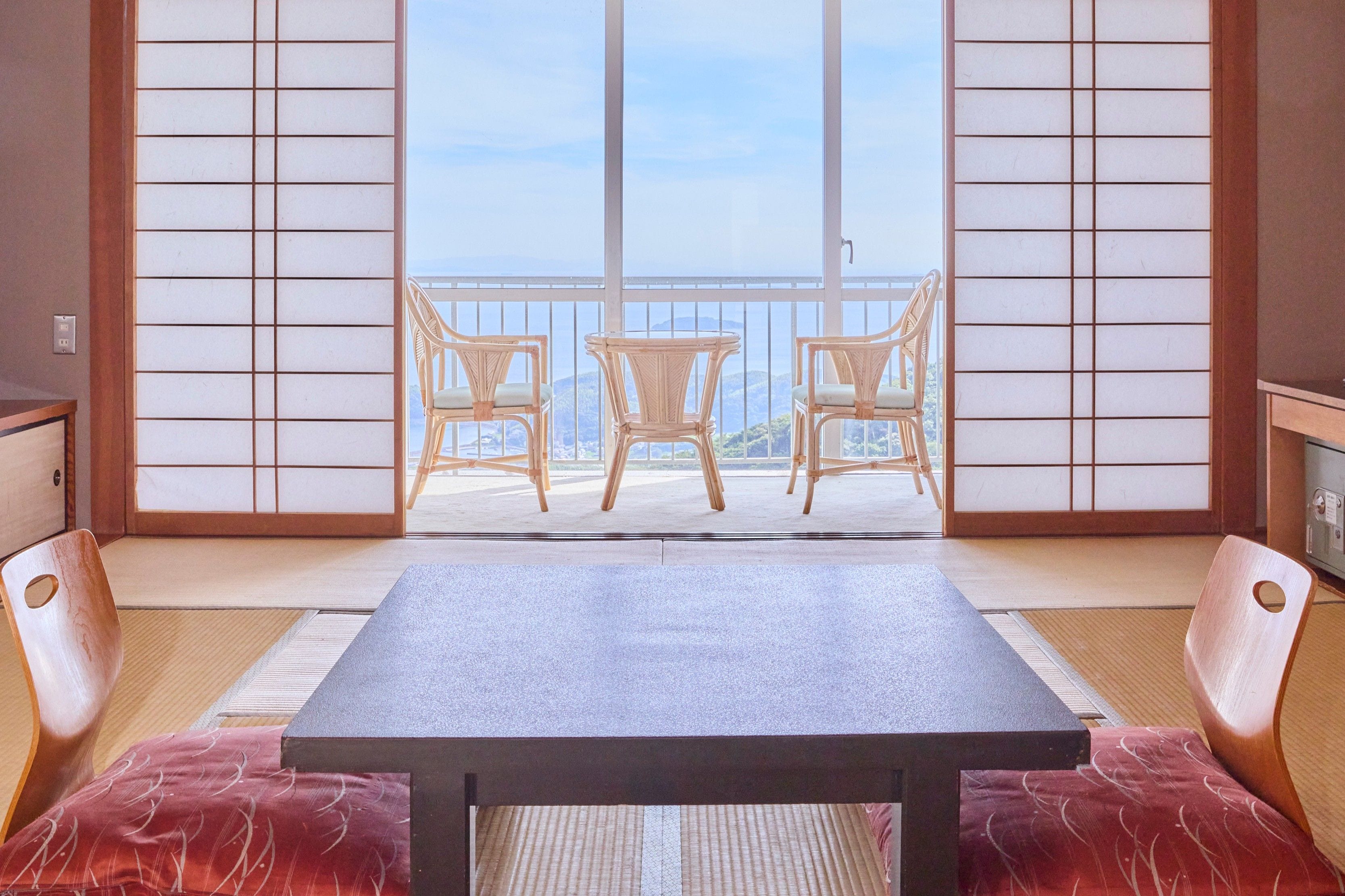 Una habitación japonesa tradicional con suelo de tatami, una mesa baja y dos sillas.