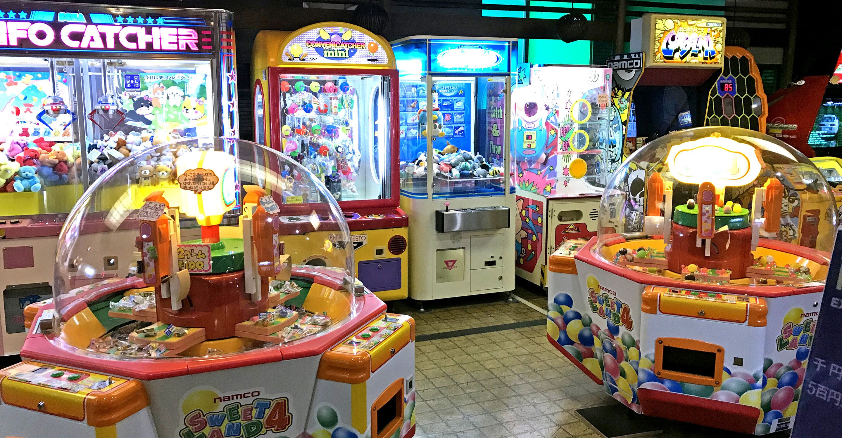A row of brightly lit arcade games with various colorful displays and prizes inside.