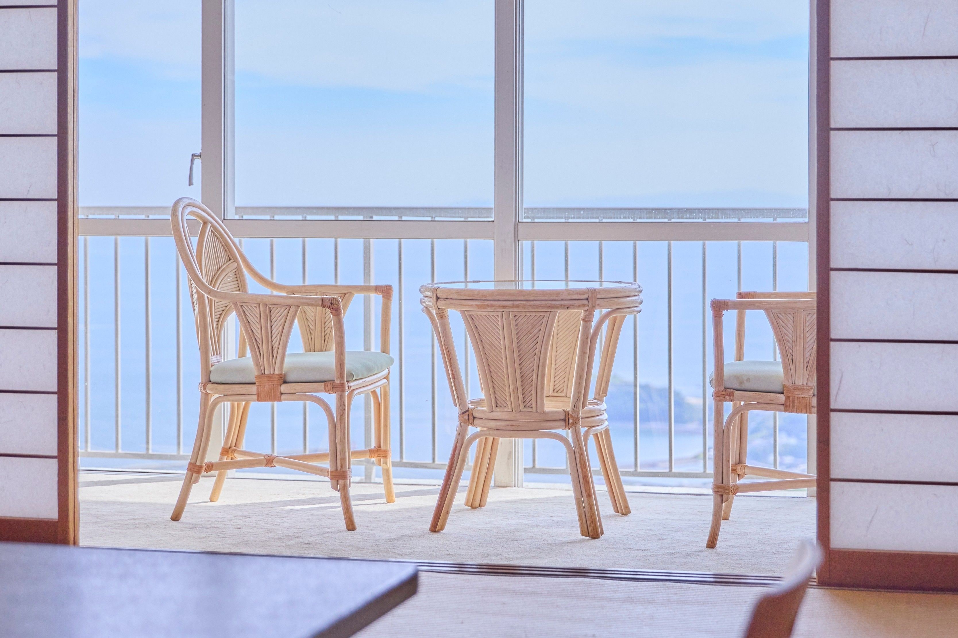 A balcony with wicker furniture and a view of the sea.