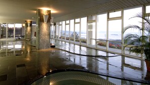 Un espacio interior amplio con suelo mojado, ventanas grandes y vista al mar.