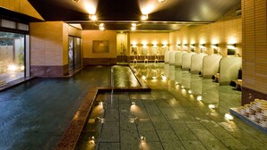 Baño público con varios lavamanos, suelo mojado y piso de baldosas.