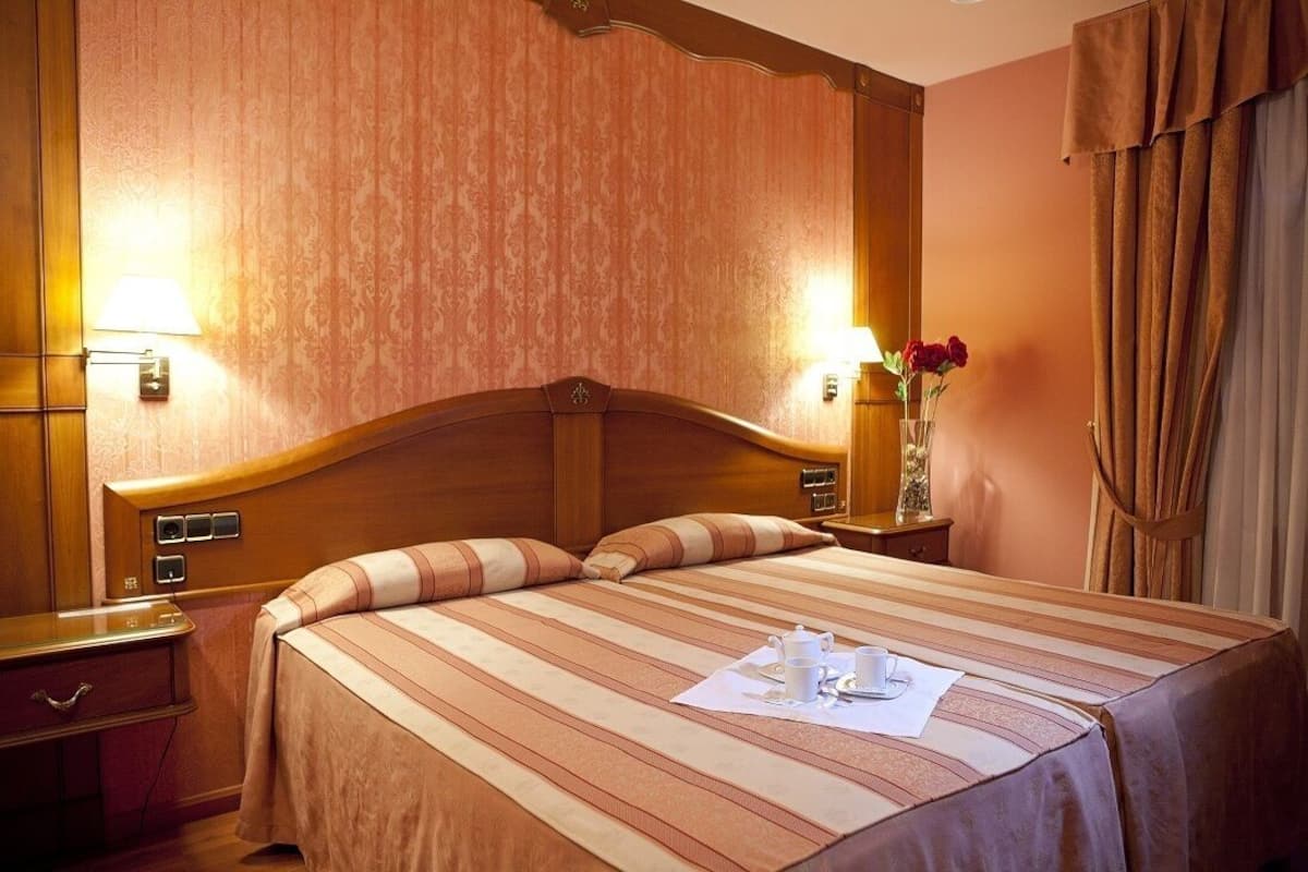 Ein Hotelzimmer mit einem großen Bett, einem Holzkopfteil, zwei Nachttischen und einem Beistelltisch.