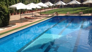 Une piscine avec des chaises longues et des parasols.