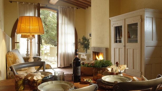 A dining area with a table set for two, a fireplace, and a view of the outdoors. - "PERA1" APARTMENT (Castellina in Chianti)