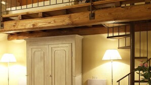 A bedroom with a wooden ceiling, a large wardrobe, two bedside tables with lamps, and a bed with a blanket. - "PERA1" APARTMENT (Castellina in Chianti)