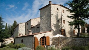 A stone building with a courtyard, featuring a wooden door and a white umbrella. - "PERA1" APARTMENT (Castellina in Chianti)