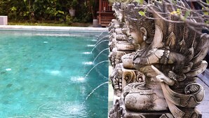 A pool with clear water and a row of stone statues. - Dewantara Resort Bali (Gerokgak)