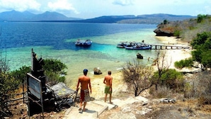 A coastal scene with a clear view of the sea, boats, and a wooden pier. - Dewantara Resort Bali (Gerokgak)