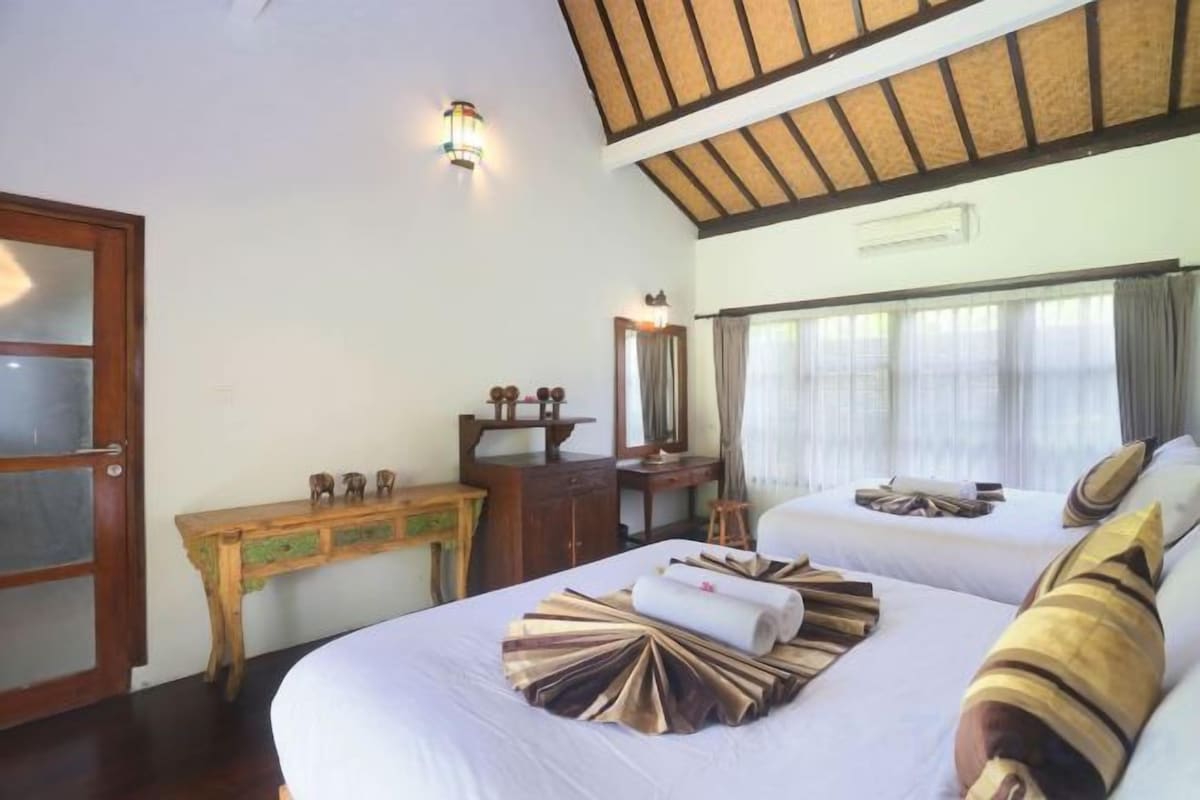 A hotel room with a large bed, a desk, a mirror, and a window with curtains.