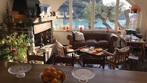 A cozy living room with a fireplace, a Christmas tree, and a view of the sea. - Relais Santa Caterina (Portovenere)