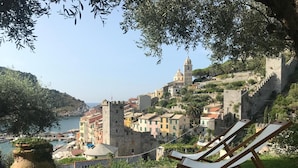 A coastal town with historic buildings, a prominent tower, and a view of the sea. - Relais Santa Caterina (Portovenere)