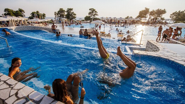 Un espace piscine comprenant plusieurs bassins, des chaises longues et des parasols.