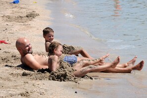 A beach scene with people lying in the sand near the water's edge.