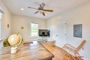 Un salon avec une table en bois, un globe terrestre, un téléviseur et un ventilateur de plafond.