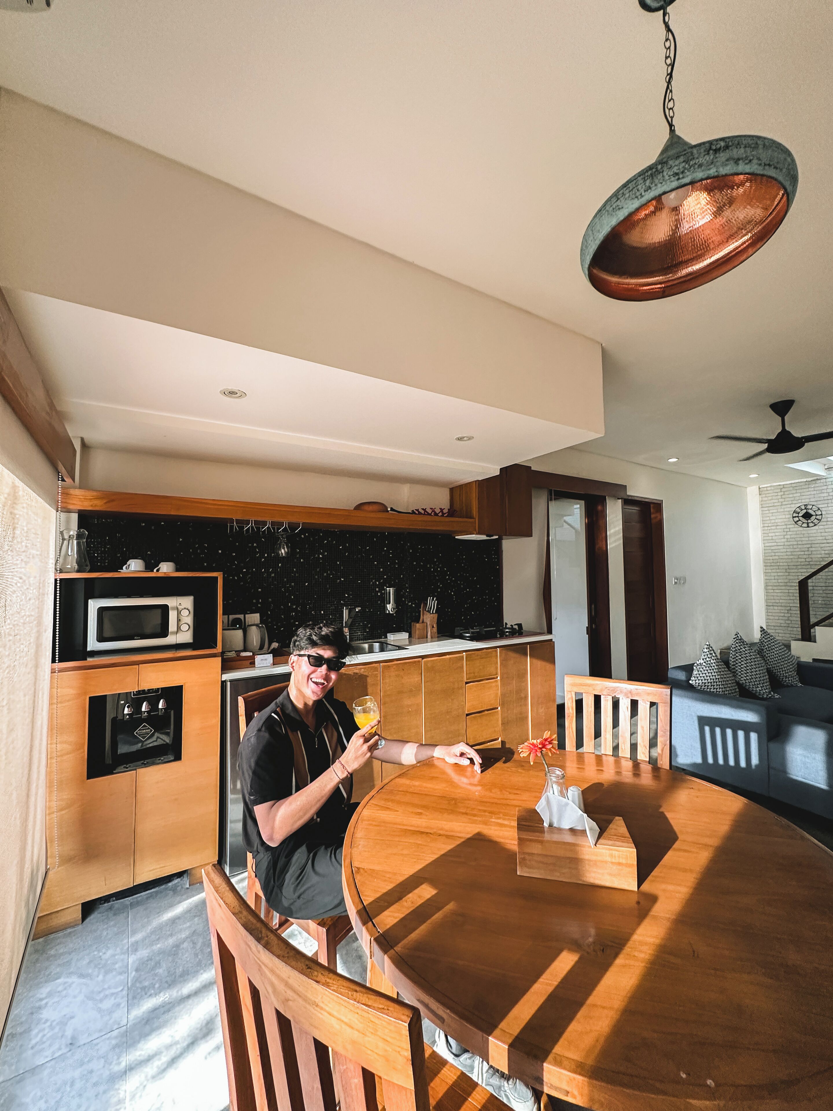 A modern kitchen with wooden cabinetry, a built-in microwave, and a round dining table with chairs.