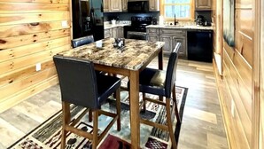 Un interior de madera con una mesa de comedor, sillas, electrodomésticos de cocina y una ventana.