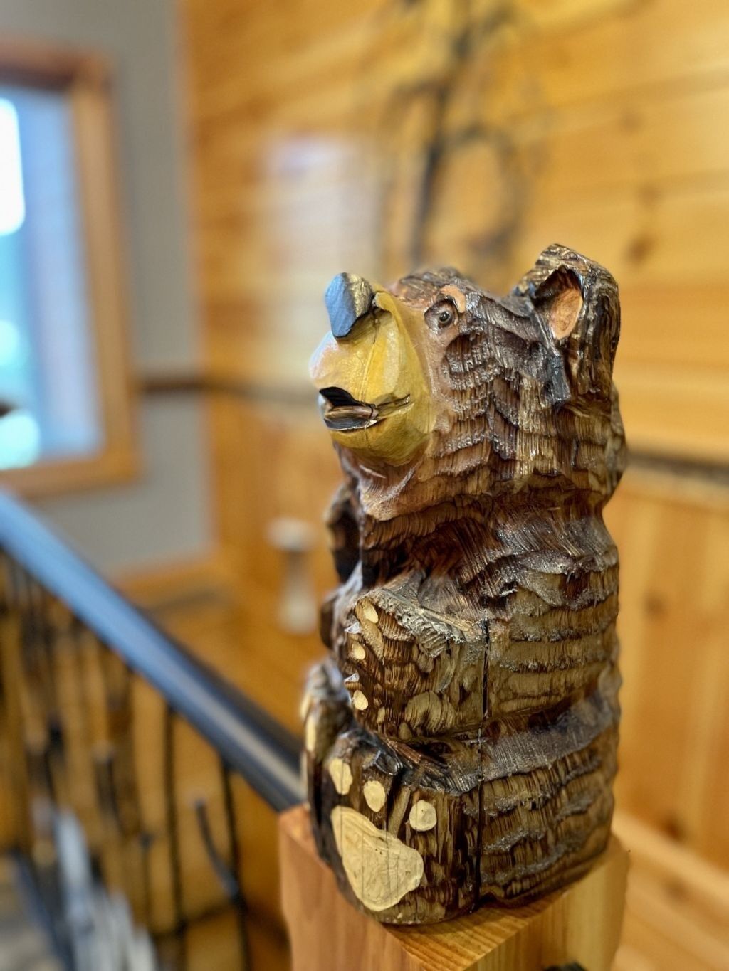 A wooden bear sculpture on a wooden stand.