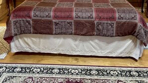 Ein schlicht eingerichtetes Schlafzimmer im Chalet-Stil mit einem großen Bett, zwei Nachttischlampen und einem gerahmten Bild an der Wand.