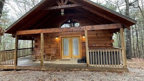 Eine Holzhütte mit Veranda, zwei Türen und einer kleinen Terrasse.