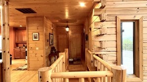 A wooden interior with a central staircase, wooden walls, and a door leading outside. - A true log cabin with 360 degree mountain views - Pet and Motorcycle friendly! 5 Bedroom Cabin by RedAwning (Tellico Plains)