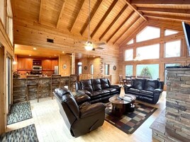 A spacious living area with leather sofas, a coffee table, and a stone fireplace.