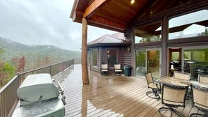 A wooden deck with outdoor furniture, a grill, and a glass-enclosed area with chairs. - A true log cabin with 360 degree mountain views - Pet and Motorcycle friendly! 5 Bedroom Cabin by RedAwning (Tellico Plains)