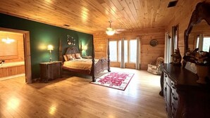 A wooden cabin bedroom with a bed, nightstands, a dresser, and a large window. - A true log cabin with 360 degree mountain views - Pet and Motorcycle friendly! 5 Bedroom Cabin by RedAwning (Tellico Plains)