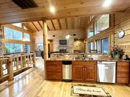 A spacious kitchen with wooden cabinets, a large island with a sink, and a built-in television.