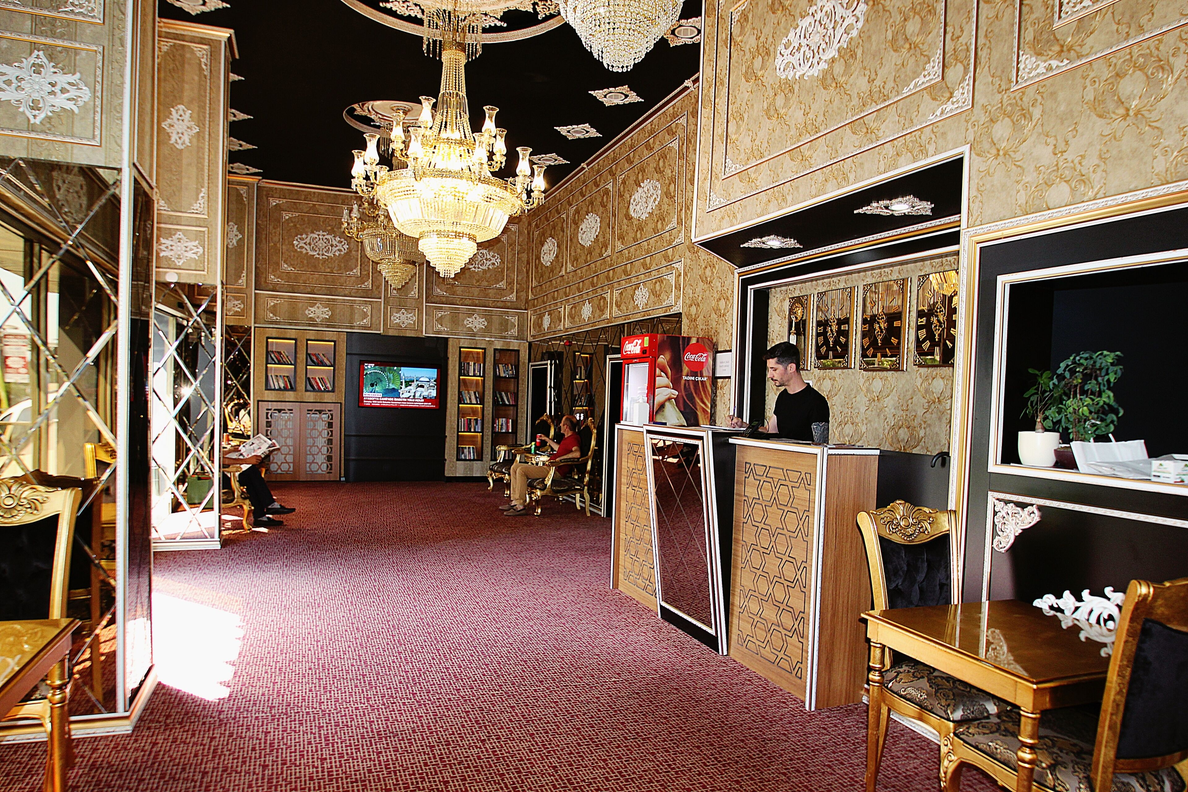Un lobby espacioso con decoración elaborada, un candelabro y un refrigerador de Coca-Cola.