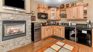 Una cucina moderna con camino in pietra, mobili in legno, forno a microonde integrato e lavastoviglie.