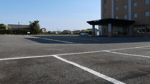 Un parking avec, au fond, un bâtiment sur lequel on peut lire l’inscription « Smile Hotel ».