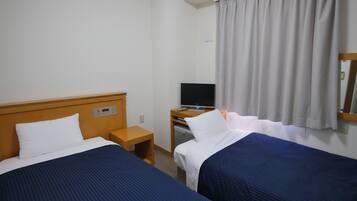 Habitación de hotel con dos camas, televisión, una mesita y ventana con cortinas.