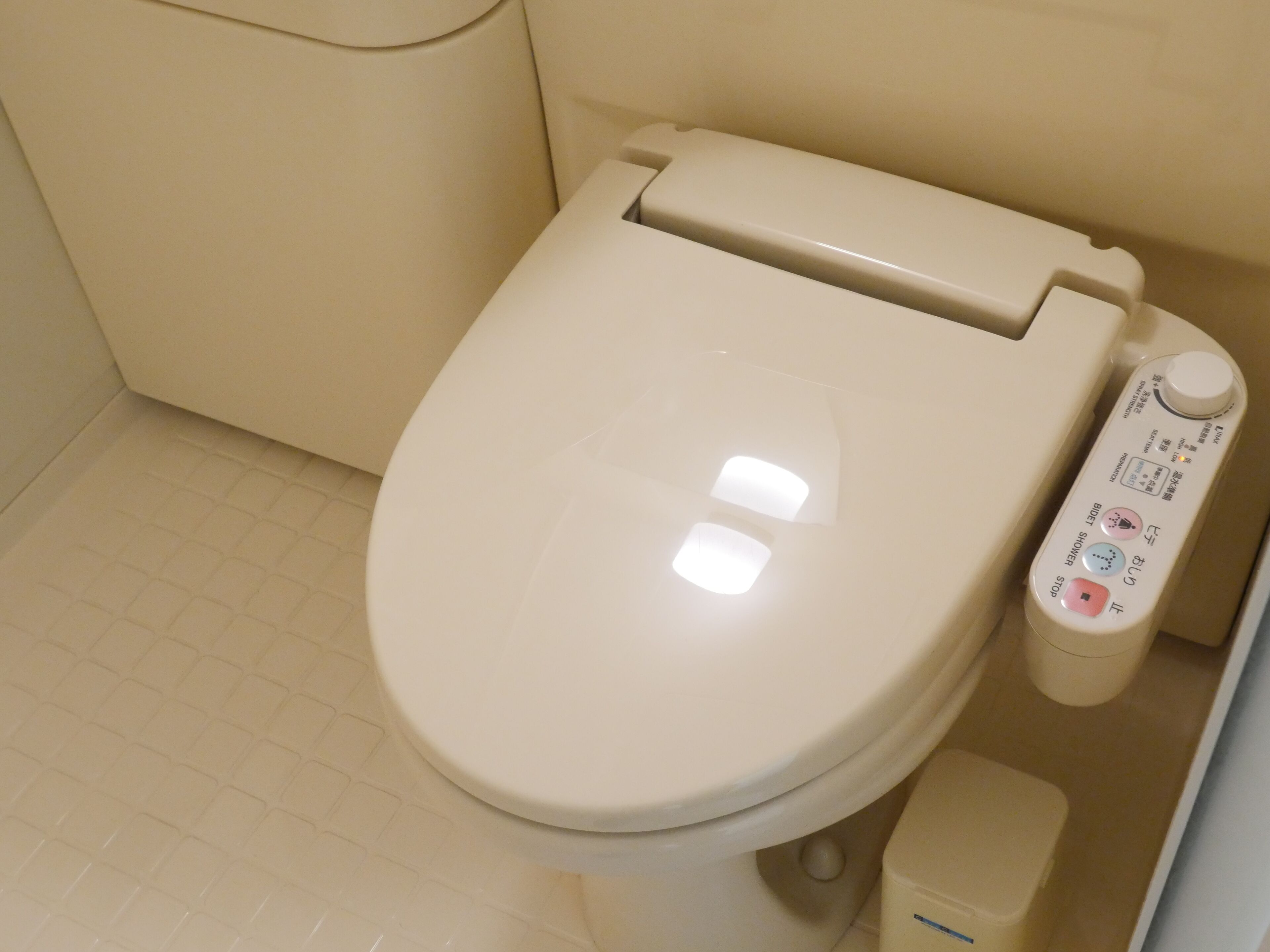A modern toilet with a control panel featuring multiple buttons and a bidet function.