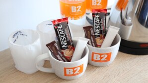 Two white mugs with B2 Boutique & Budget branding, each containing a Nescafé Blend & Brew coffee pod. - B2 Rayong Boutique and Budget Hotel (Rayong)