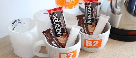 Dos tazas blancas con la marca B2 Boutique & Budget, cada una con una cápsula de café Nescafé Blend & Brew.