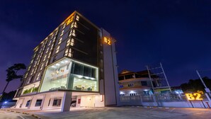 A modern hotel with a prominent B2 sign, large windows, and a well-lit entrance. - B2 Rayong Boutique and Budget Hotel (Rayong)