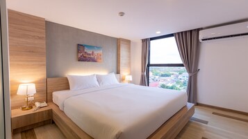 Et moderne hotelværelse med en stor seng, udsigt over bybilledet, et ophængt billede og en telefon på natbordet.