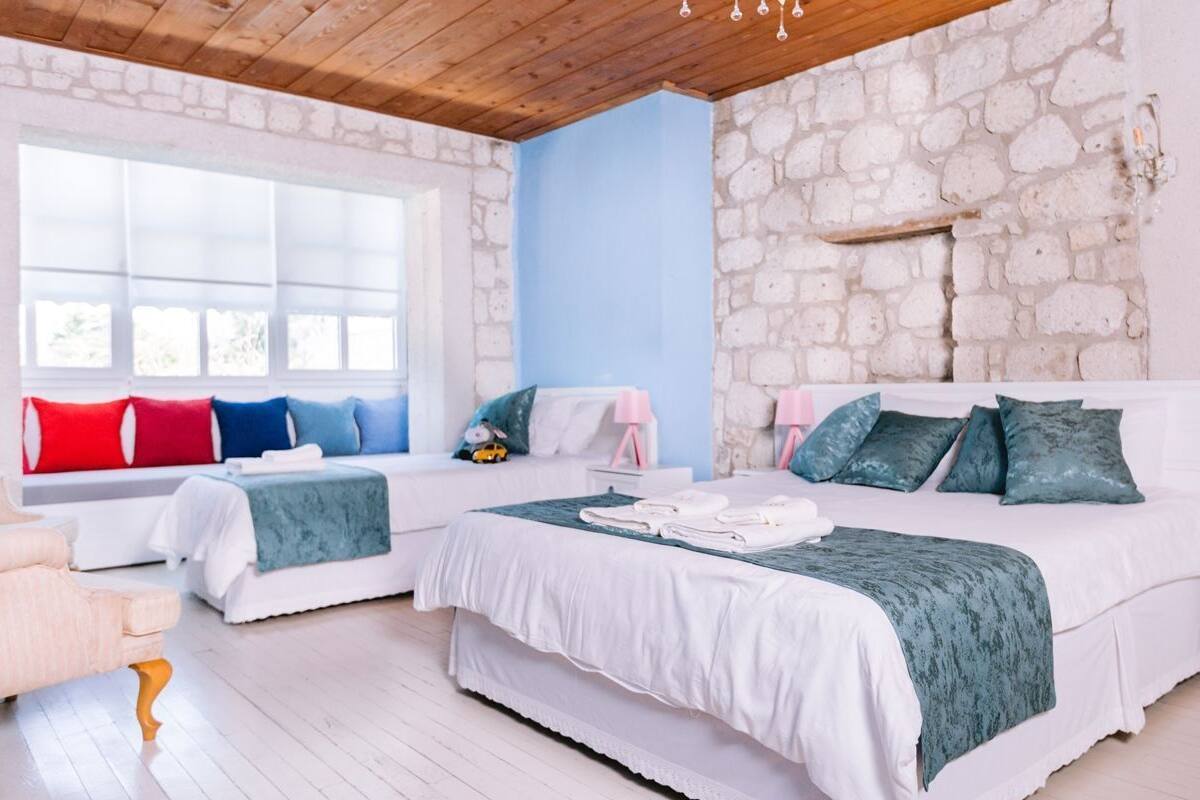 Un dormitorio con dos camas, una pared de piedra, un ventanal grande y techo de madera.