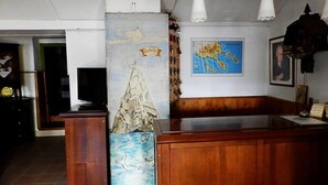 Een houten receptiebalie met een kaart en een ingelijste foto aan de muur.
