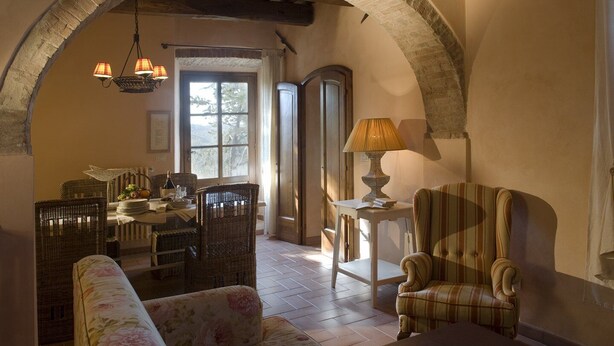Une pièce chaleureuse avec une table à manger, des chaises en osier, un canapé à motifs floraux et un fauteuil à rayures.