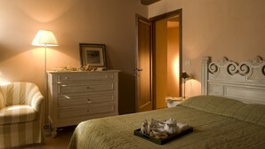 Une chambre à coucher avec un lit, une commode, une chaise et une table de chevet avec une lampe.