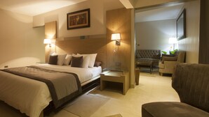 A hotel room with a bed, bedside tables, a chair, a sofa, and a television. - Hotel VDN by Good Rade (Dakar)