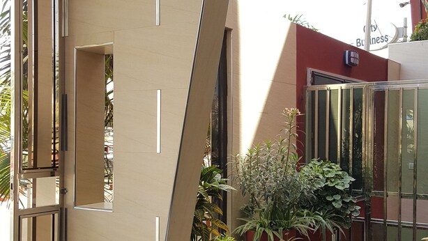 A modern building with a unique angular design, featuring a glass entrance and potted plants. - Hotel VDN by Good Rade (Dakar)