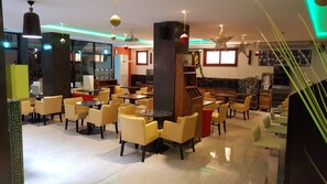 Un restaurant moderne avec des chaises jaunes, un coin bar et un éclairage décoratif.