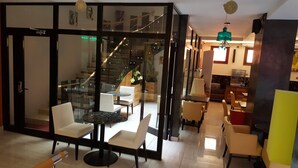 A modern interior with glass walls, a staircase, and a dining area with white chairs and a round table. - Hotel VDN by Good Rade (Dakar)