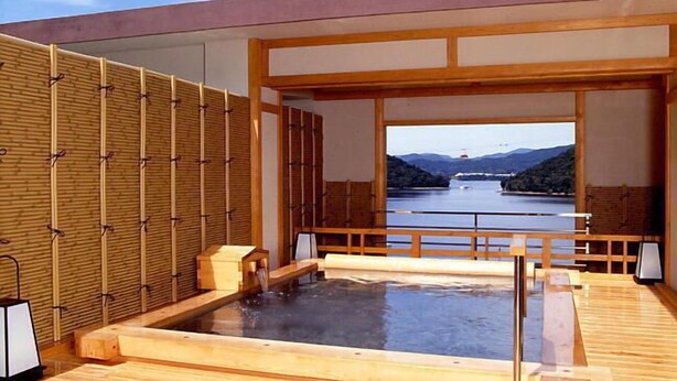 A modern spa with a wooden deck, a hot tub, and a view of a lake and mountains. - Hamanako Kanzanjionsen Hotel Kikusuitei (Hamamatsu)