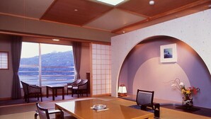 A room with tatami flooring, a wooden table, chairs, a view of the sea, and a traditional Japanese-style lamp. - Hamanako Kanzanjionsen Hotel Kikusuitei (Hamamatsu)