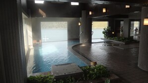 An indoor swimming pool with a view of the sea, surrounded by pillars and a tiled floor. - Hamanako Kanzanjionsen Hotel Kikusuitei (Hamamatsu)
