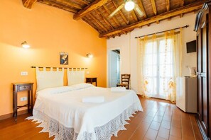 A bedroom with a wooden ceiling, a bed with white bedding, a nightstand, a chair, and a television. - Agriturismo La Quercia (Scansano)
